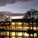 傍晚时分托马斯·库珀图书馆的正面视图，摄于反射池对面。图书馆窗户上的灯光反射在水面上。