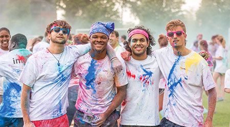 在“彩色奔跑”中，4名学生穿着溅满彩色粉笔的白衬衫，手挽着手，对着摄像机摆出各种姿势。