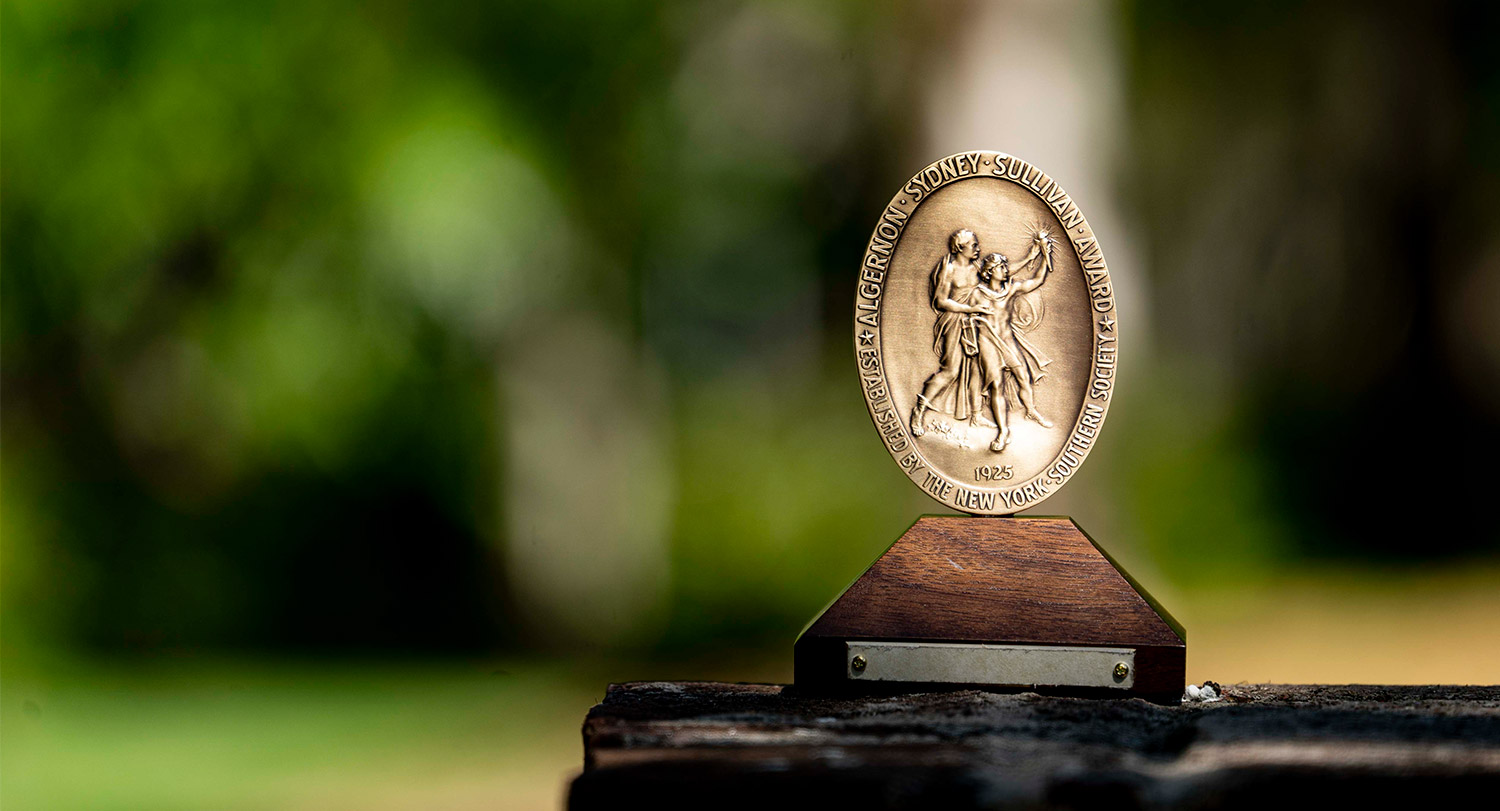 青铜阿尔杰农悉尼沙利文奖坐在室外木桌上。