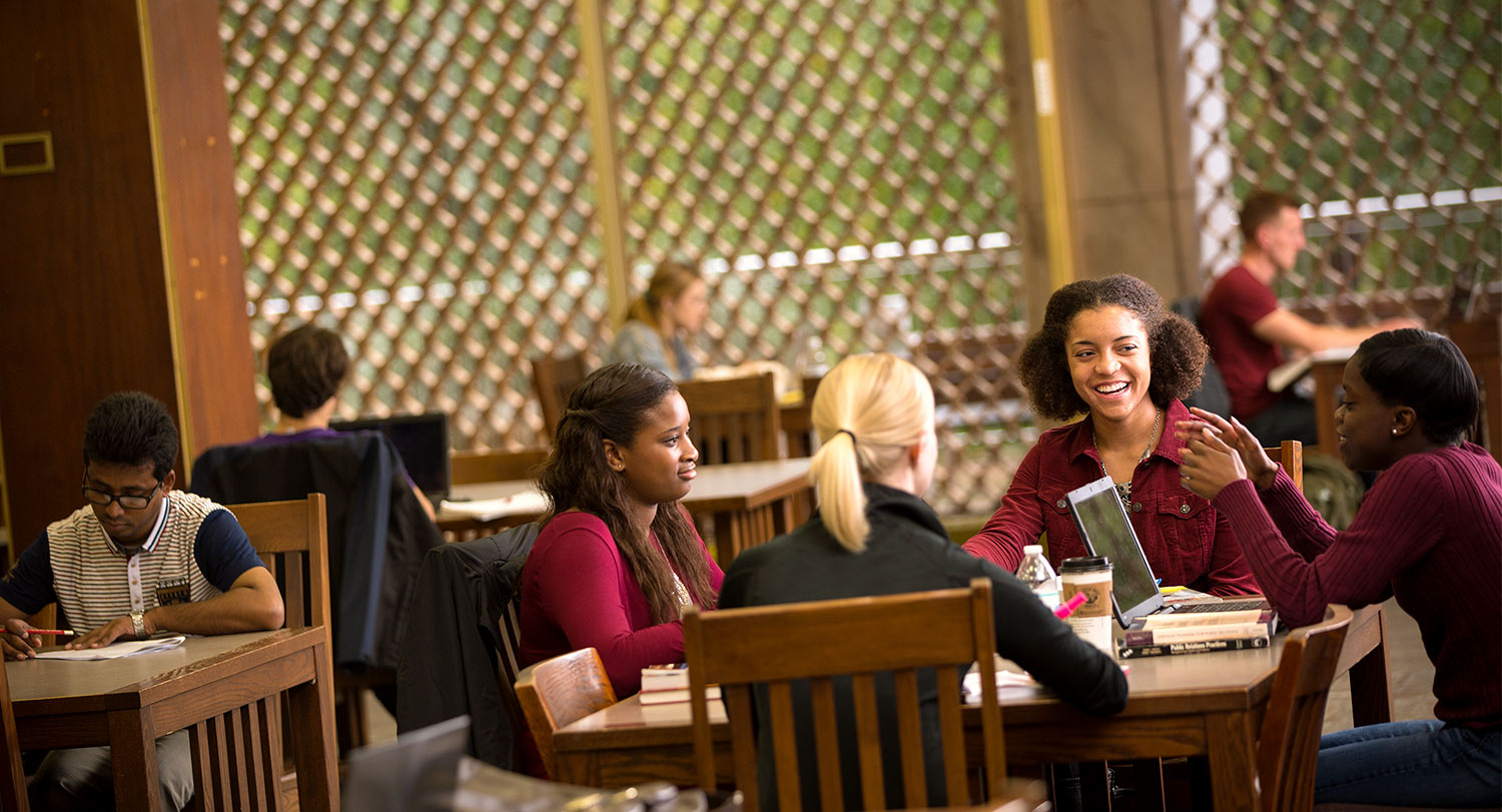 在图书馆的一张桌子旁一起学习的一群学生。