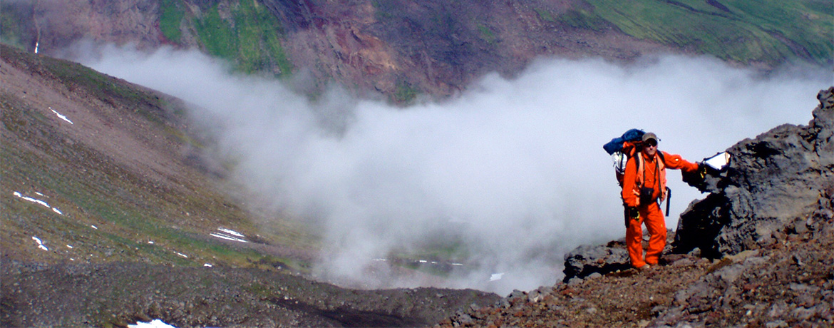 背包客在温泉的蒸汽云前摆姿势