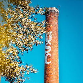 蓝色的天空前，烟囱上有USC的字母，周围是树枝。