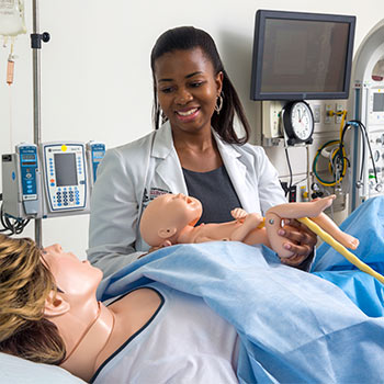 学生抱着一个医学实习婴儿，另一个实习病人作为母亲。