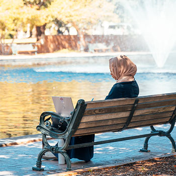 学生坐在水池旁的长凳上。