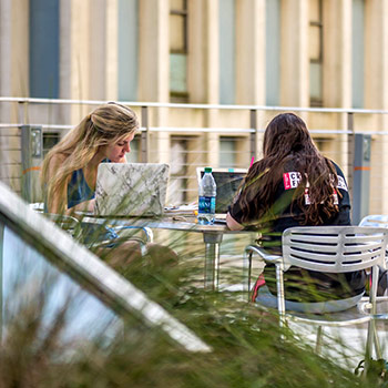 学生们在户外桌子旁学习。