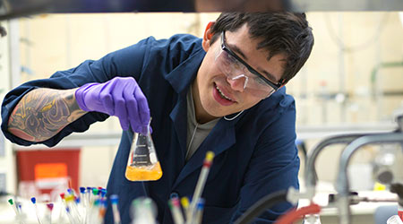 一个学生在实验室长凳上旋转烧杯里的黄色液体。