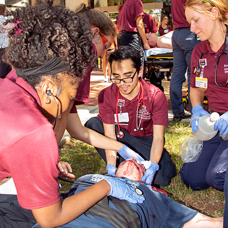 在急救训练课程中协助病人的医学生。