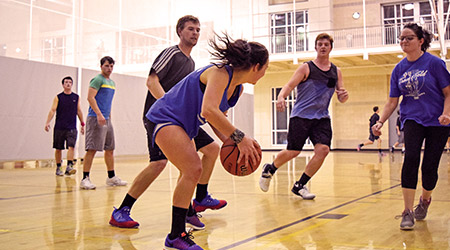 男女学生在健康中心的球场上打篮球。