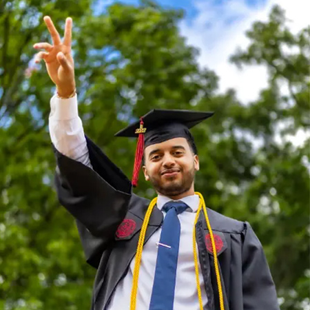 毕业生举起手臂，对着镜头挥舞手指。