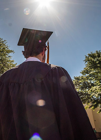 后面的学生戴着毕业帽和毕业服，背景是蓝天。