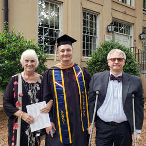 威廉·布朗头戴毕业帽，身穿毕业礼服，和父母站在一起
