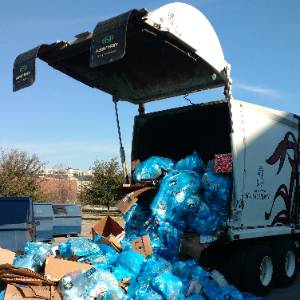 一个大型垃圾卡车装满了蓝色的垃圾袋