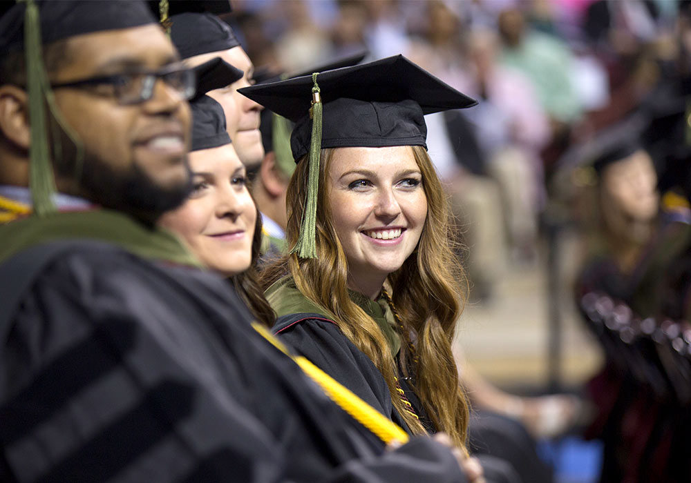 戴着毕业帽和毕业服的学生在毕业典礼上微笑。