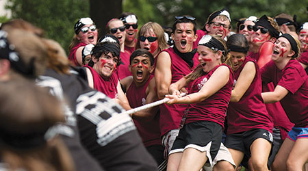 学生们穿着石榴色和黑色衬衫，涂着脸，正在进行激烈的拔河比赛。